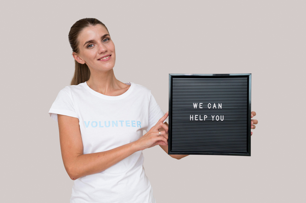 image of a woman volunteer showing banner saying: we can help you